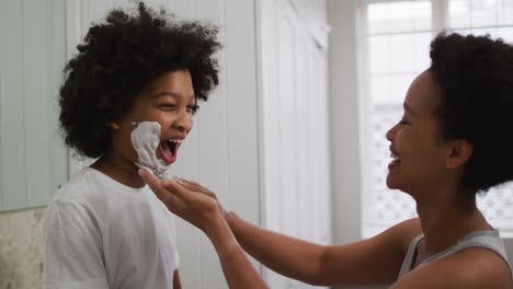 mixed race mother and daughter having fun in bathroom