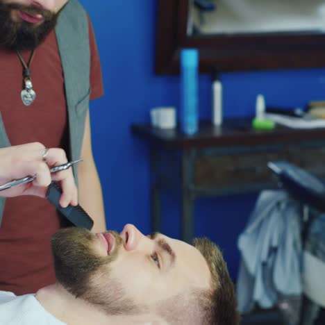 tilt down of barber working on client's hair and bear