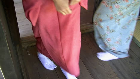 japanese women wearing kimonos and tabi socks walk through doorway on hinoki wood floor