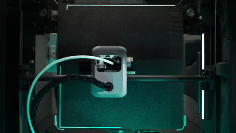 3d printing chamber top view: the extruder mounted on a rail prints the object with filament delivered through a bowden tube