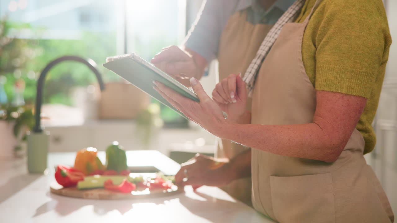 野菜を準備しながらレシピをタブレットで確認するカップル