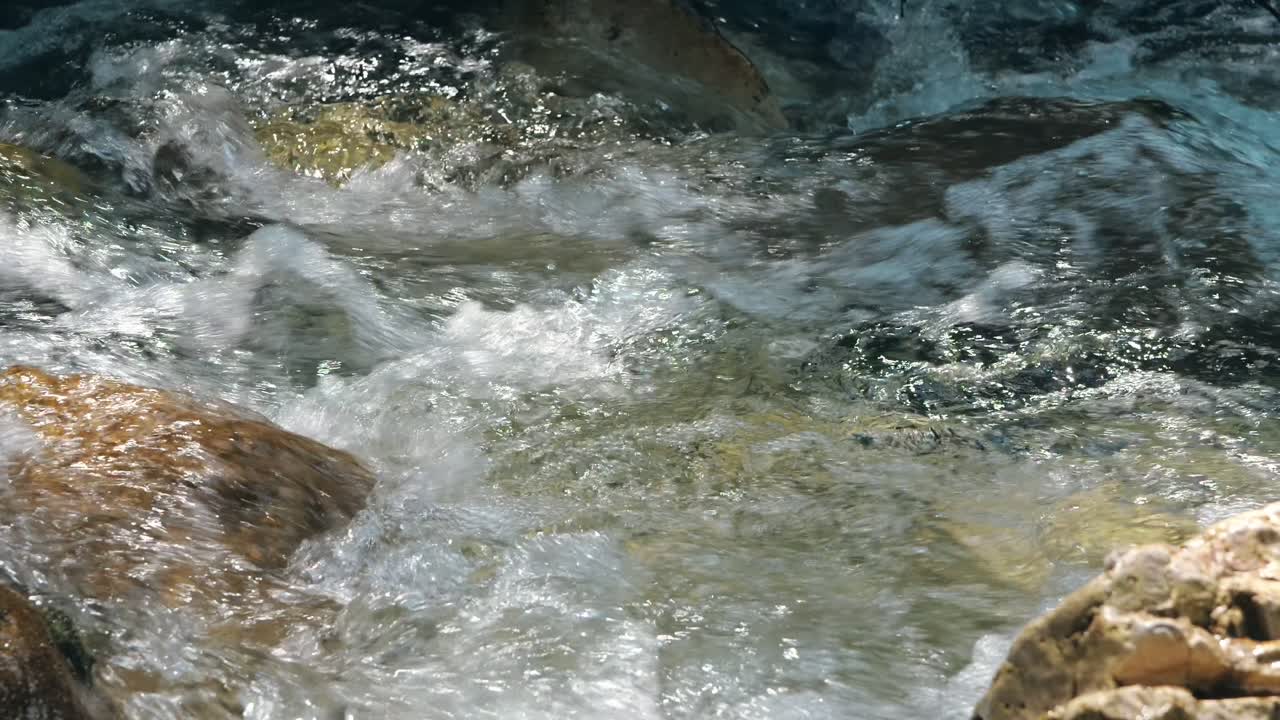 Acqua impetuosa che scorre tra le pietre. Raggi di sole che cadono sulle pietre bagnate e un fiume pulito.