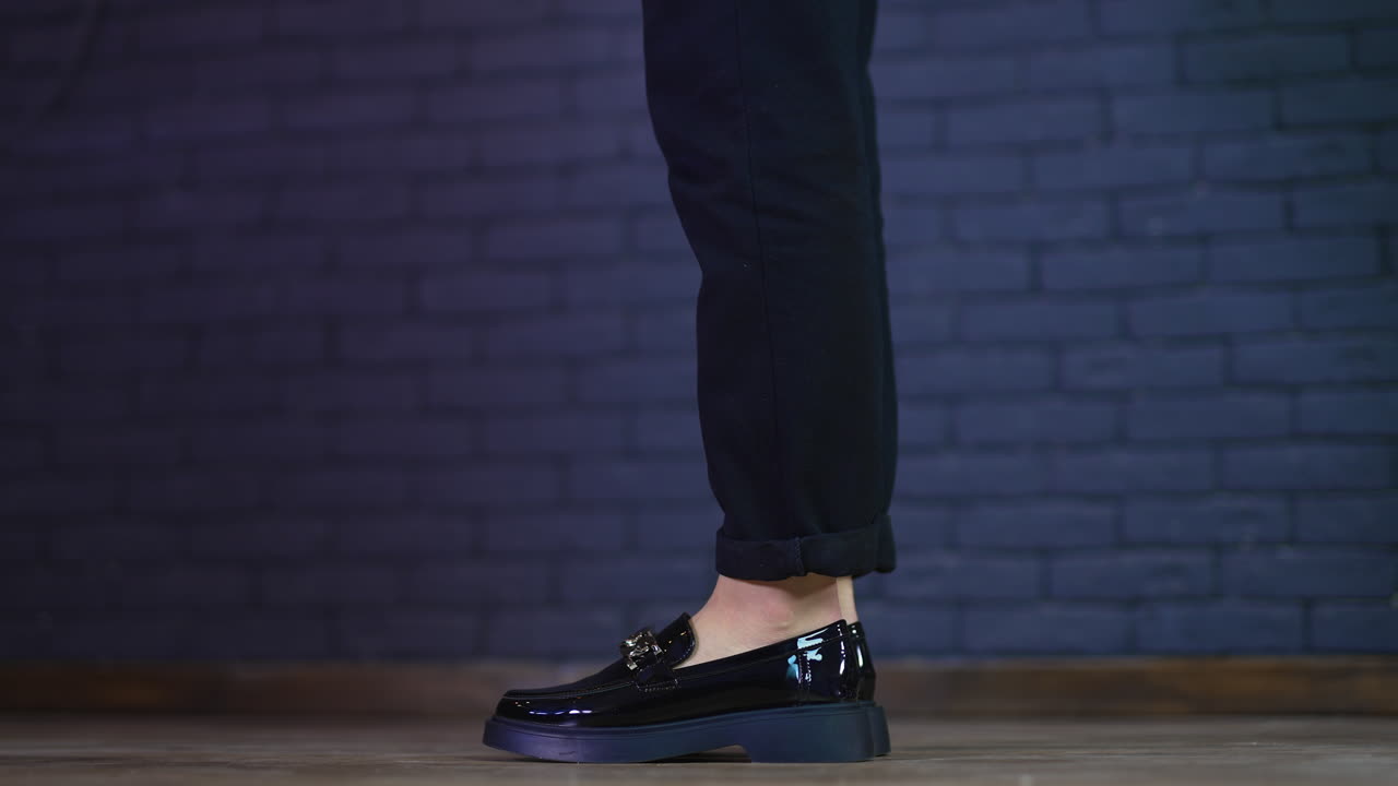 Female model in black beautiful lacquered shoes jumps up to stand on toes. Fashionable designer footwear demonstration. Close up.