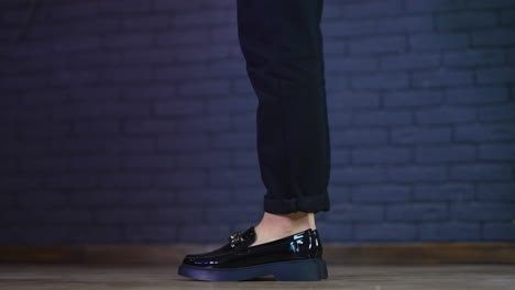 female model in black beautiful lacquered shoes jumps up to stand on toes. fashionable designer footwear demonstration. close up.