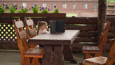 happy girl has fun watching video via tablet in restaurant