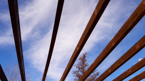 view under a construction of wooden beams and sky in the background