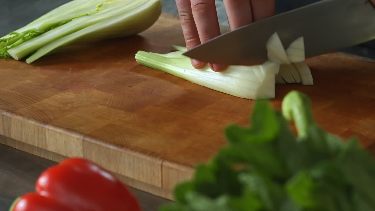 Chef carefully chopping fennel,left hand,wooden board,vegetables