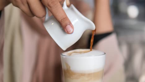 woman pouring espresso into latte