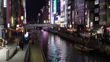 illuminated urban canal with boats and pedestrians