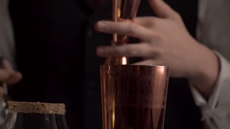 a bartender is pouring spirit into the jigger then to the copper-tin.