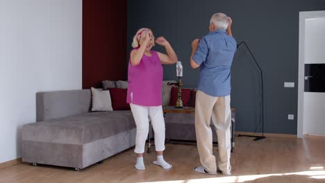 Pareja-Mayor-Bailando-Riéndose-En-Casa.-Abuelos-Relajándose-Divirtiéndose-Celebrando-Aniversario