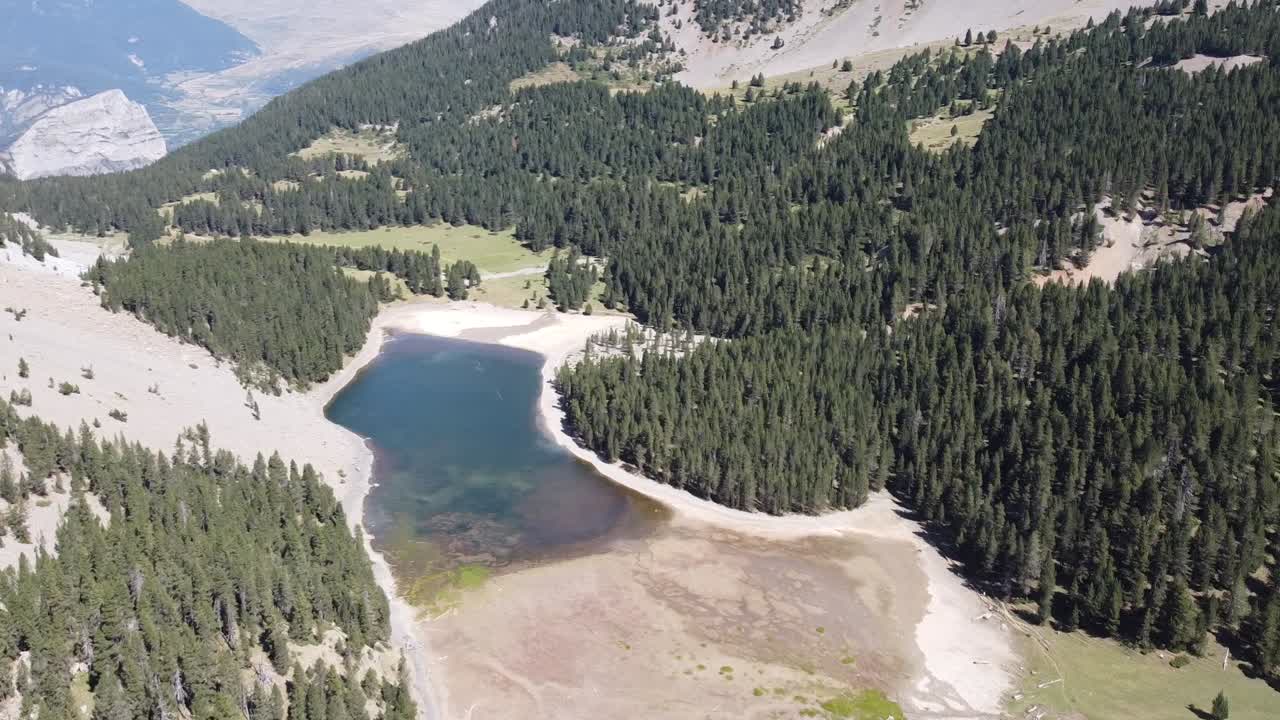 Aerial horizontal footage of a lake in a green natural environment with mountains in the Spanish Pyrenees.