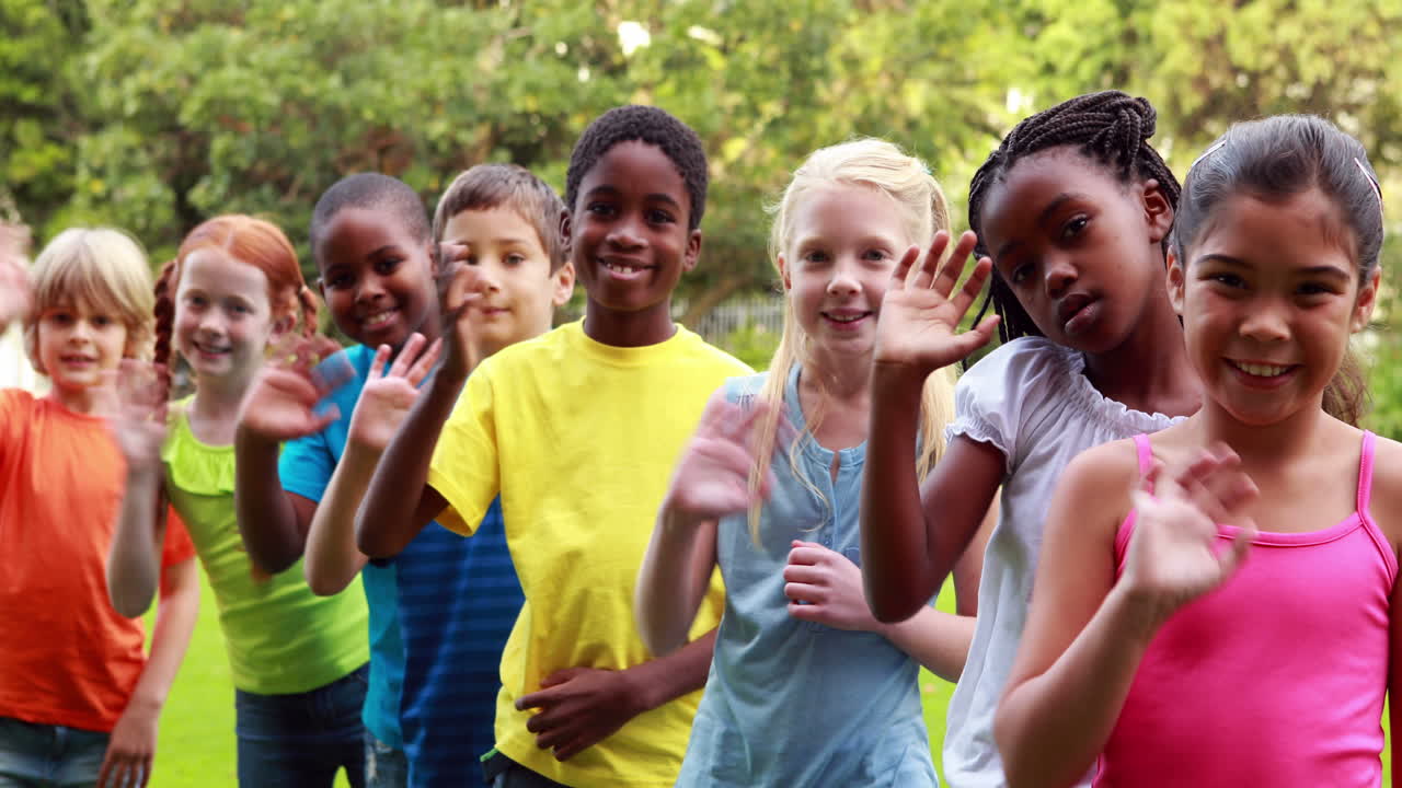 Fila de alunos acenando e sorrindo para a câmera