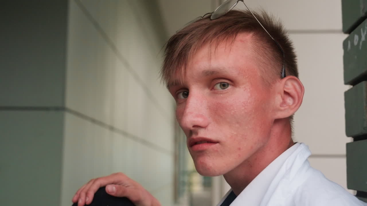Ecologist in white coat with glasses resting on head sits near wall while looking focused into distance, reflecting curiosity, observation, and thoughtful scientific attention outdoors
