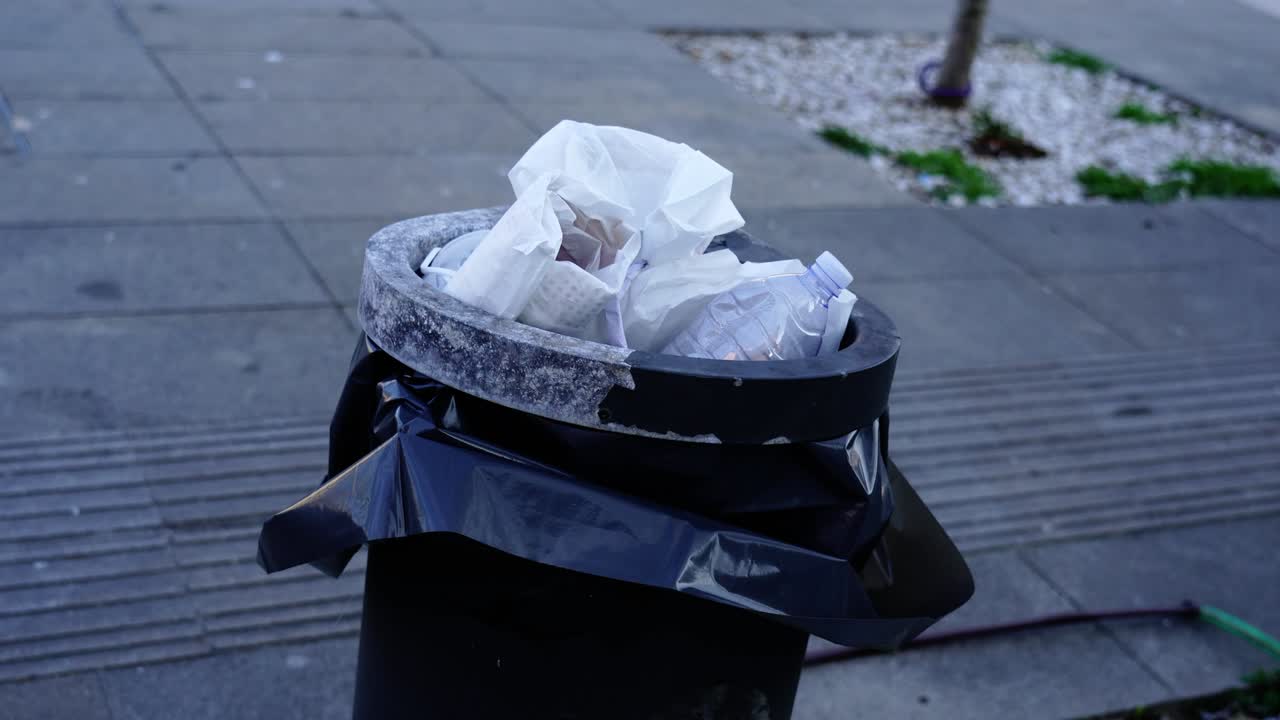 un contenedor de basura negro lleno de bolsas de plástico negras y basura