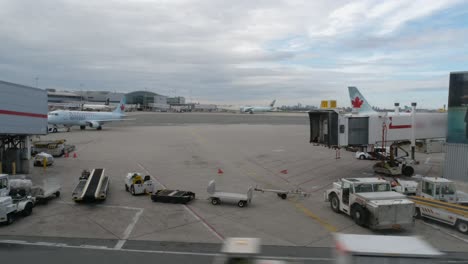 Airplane-approaches-airport-gate-while-various-vehicles-drive-around