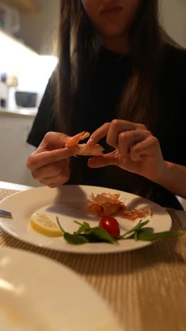una mujer comiendo camarones.