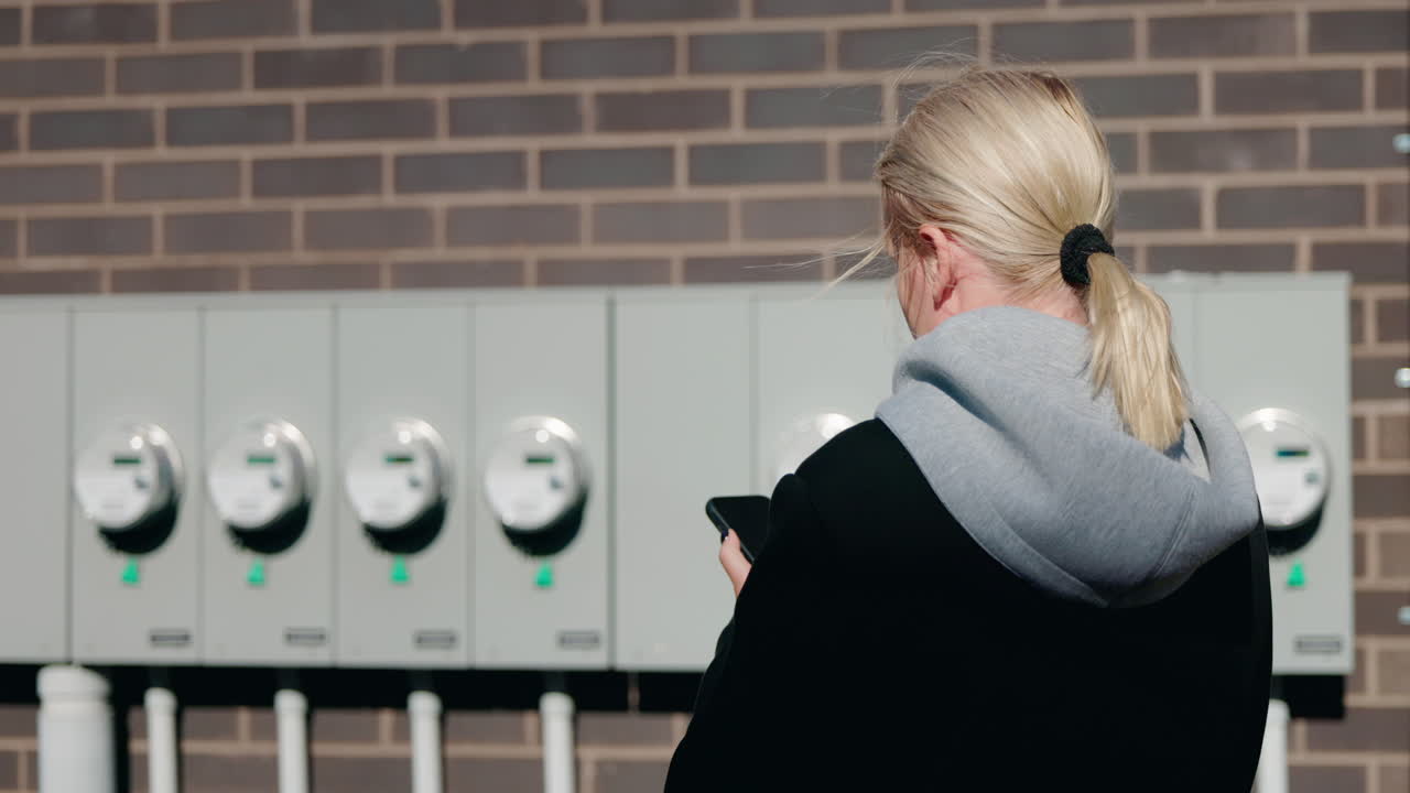Woman using phone near energy meters