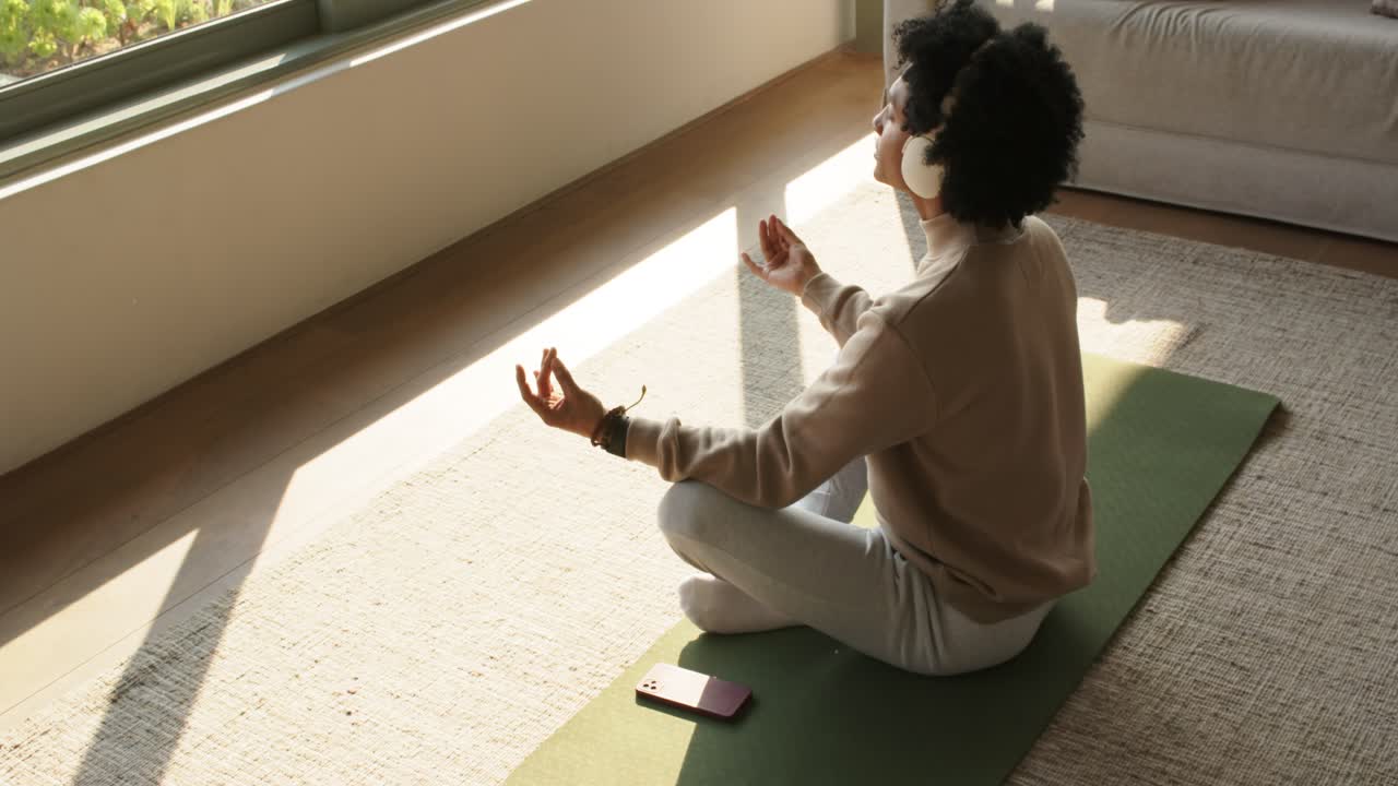 Preparazione smartphone e cuffie, uomo che medita concentrandosi sul respiro sul tappetino a casa, spazio per la copia