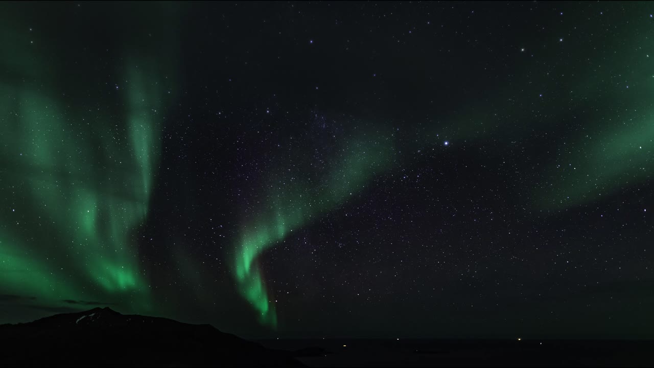 un lapso de tiempo de la aurora boreal y la vía láctea sobre el mar y las islas del norte de noruega