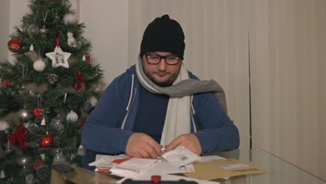 frustrated hopeless man in winter clothes checking heap of bills to pay during christmas season