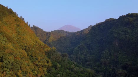 vuela sobre un acantilado empinado entre 2 colinas cubiertas de denso bosque
