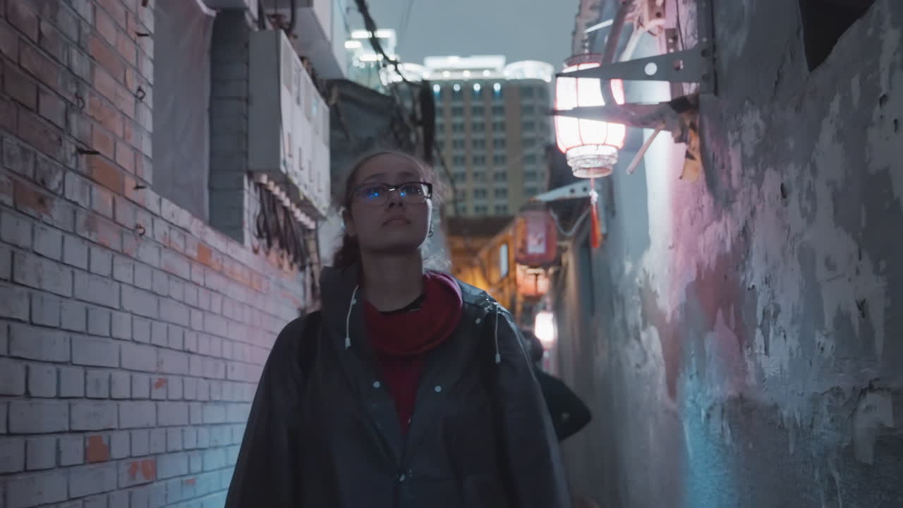 Mulher asiática explorando um beco estreito iluminado por neon, paredes de tijolos e brilho de lanternas, usando casaco e cachecol vermelho com óculos, um retrato cinematográfico melancólico de curiosidade urbana, estudante viajante se aventurando em um local escondido.