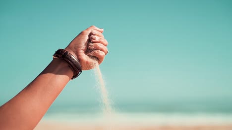 Geschlossene-Hand,-Die-An-Einem-Sonnigen-Sommerurlaubstag-Sand-Freigibt,-Der-Durch-Finger-Und-Faust-Am-Strand-Fließt-Und-Fällt