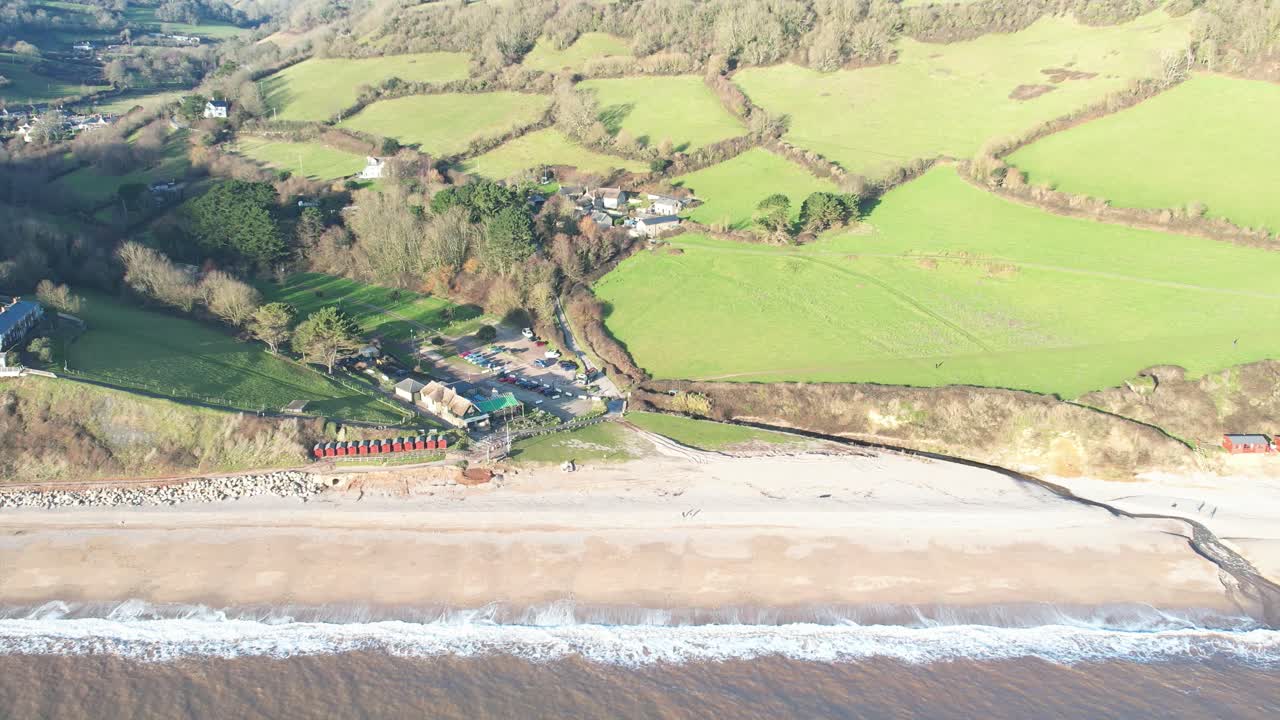 Aerial view of Branscombe beach and surrounding green fields meeting the sea in East Devon, a popular tourist destination in England.pull back shot