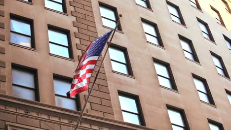 the american flag waves from a building on wall street in new york city