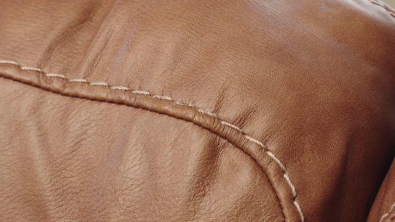 Closeup shows heat gun speeding drying of fresh paint on brown leather sofa