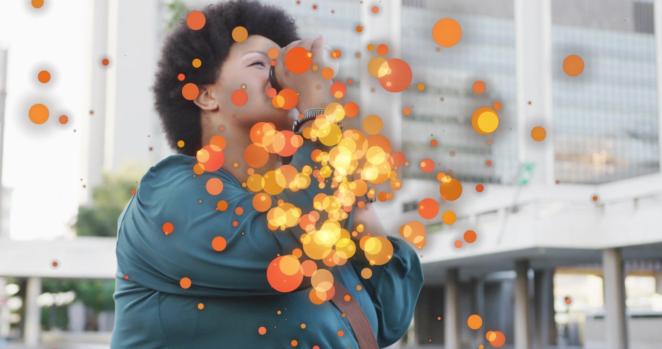 Mid adult woman sipping travel mug and releasing glowing orange dots across business plaza