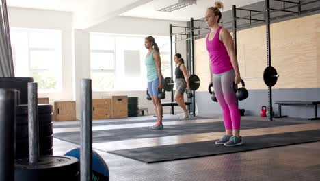 Focused-unaltered-diverse-women-group-training-at-gym-together-with-kettlebells,-in-slow-motion