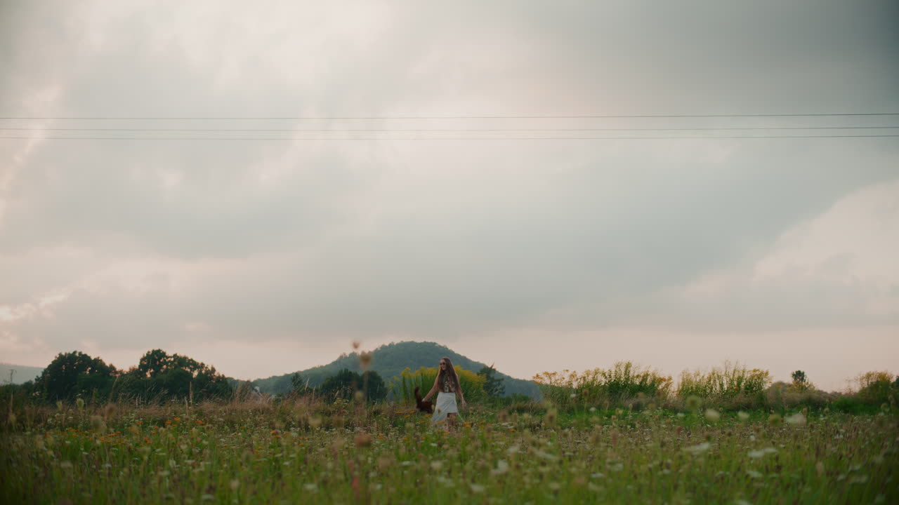 한 여인이 구름과 아름다운 초원을 배경으로 고 있습니다.
