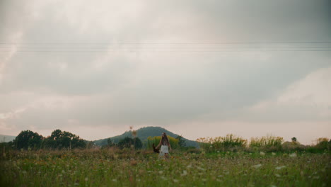 a woman walks against the backdrop of clouds and beautiful meadows