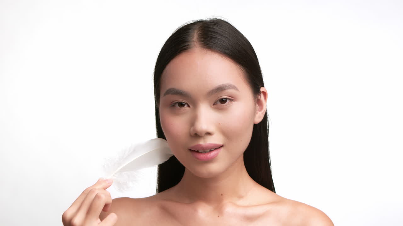 Natural Beauty: Young Asian Woman with Feather on Clear Skin