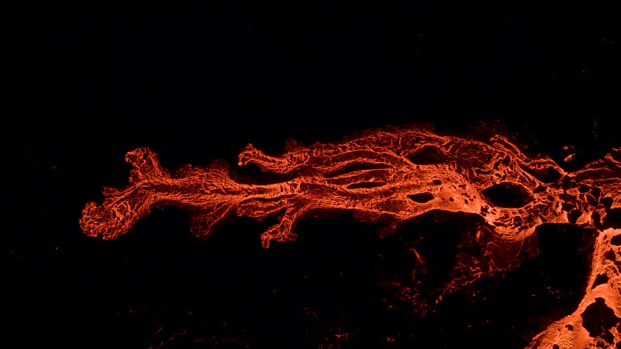 Ramo di lava che scorre su roccia scura di notte, vista dall'alto