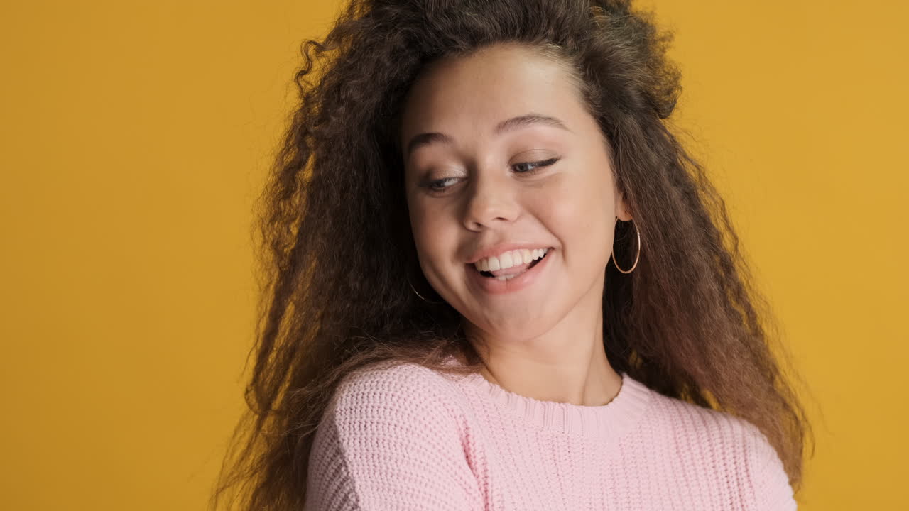 Caucasian curly haired woman smiling to the camera.