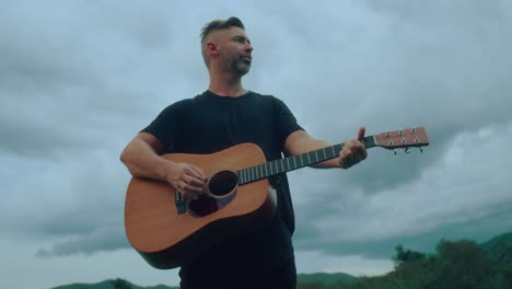 hombre tocando la guitarra acústica al aire libre