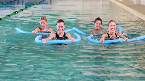 four women doing aqua aerobics smiling at camera