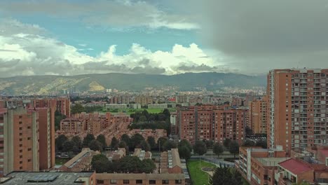 A-drone-flying-between-some-buildings-with-the-mountain-in-background