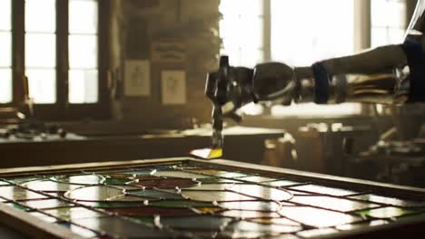 in a bright workshop filled with glass, a robotic arm carefully assembles vibrant stained glass pieces, showcasing precision in art. the intricate details shine as the arm works diligently.