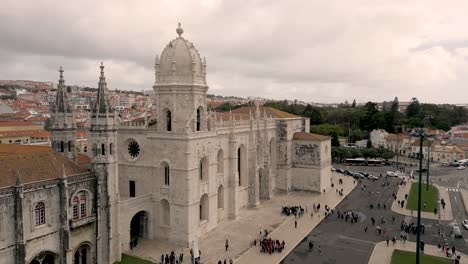 astounding gothic style of jeronimos monastery with tourists outside the building on a cloudy day in belem, lisbon, portugal