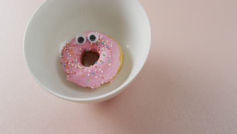 video of donut with icing on white plate over pink background