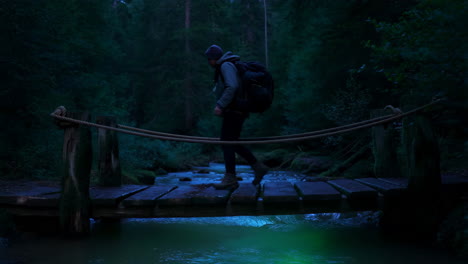 person crossing a glowing river on a wooden bridge in a dark forest