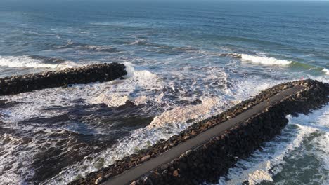 Aerial view of ocean waves hitting a stone breakwater at Brunswick Heads, NSW. Captured in natural daylight with dynamic movement