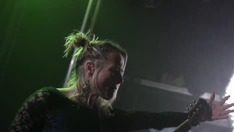 Young-professional-woman-vocalist-performing-in-night-club-lights-with-guitar-close-up-slow-motion