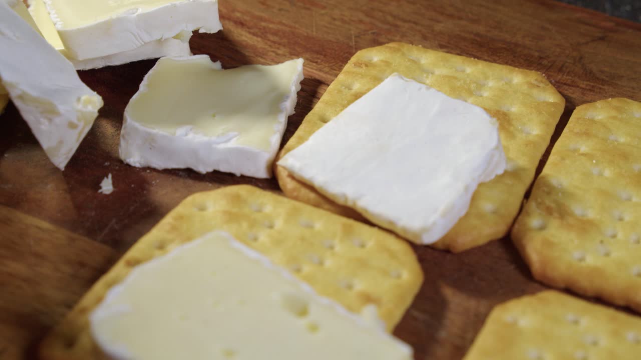 primer plano: pedazos de queso brie colocados sobre galletas de soda saladas