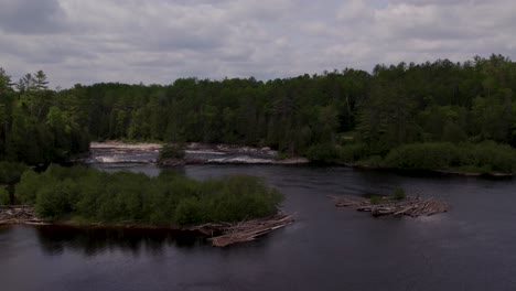 A descending drone shot of a flat stretch of the Gatineau River heading towards the rapids