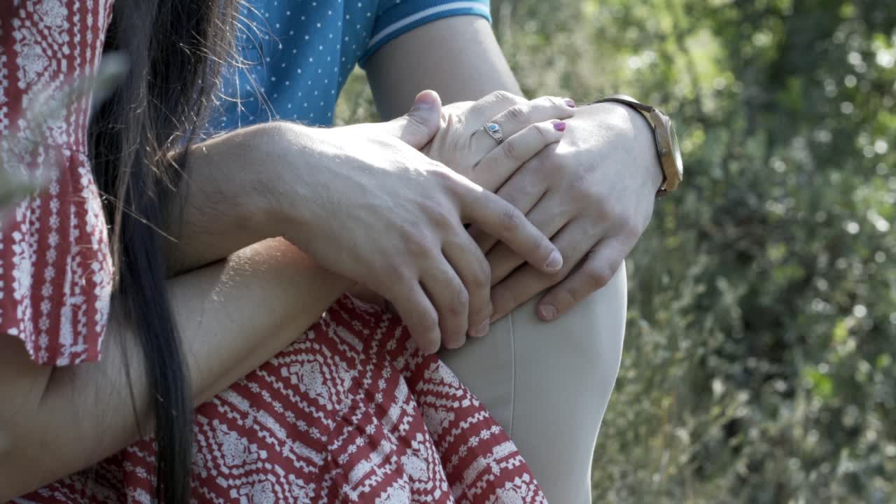 un hombre con una camisa azul está sentado y sosteniendo el brazo de una chica con un vestido de color rosa